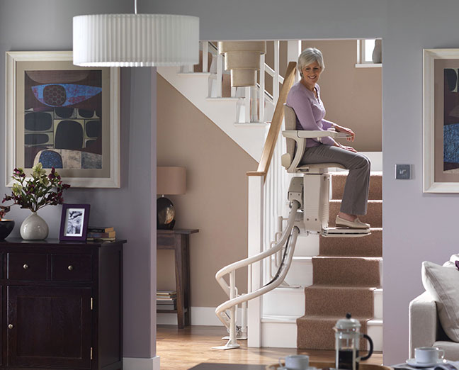 elderly woman using a curved stair chair lift