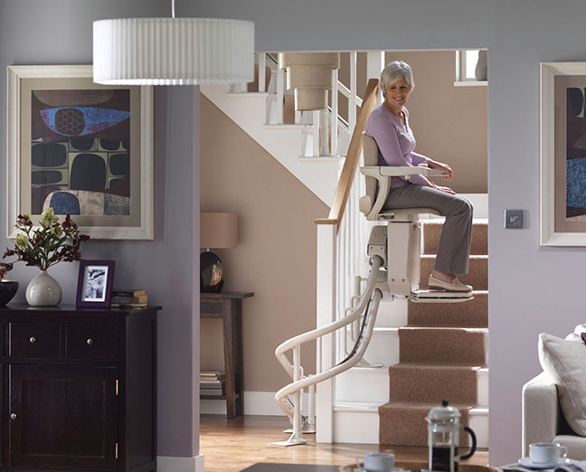 elderly woman using a curved stair chair lift